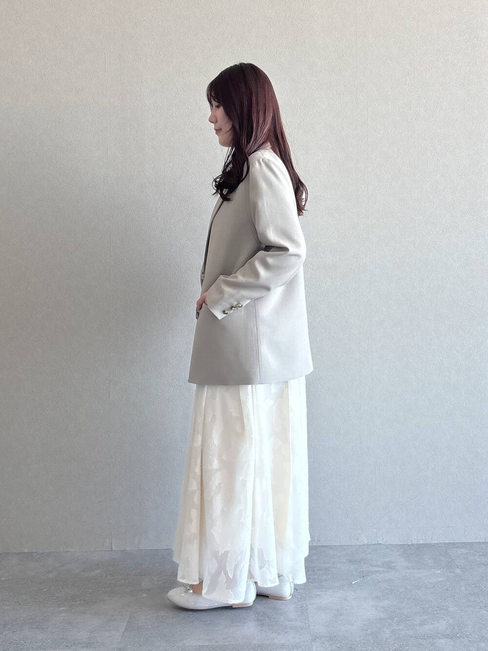 ベージュ系のテーラードジャケット、シルバー系のバレエシューズ、ホワイト系のワンピースを着用したレディースの冬コーディネートの2枚目の写真