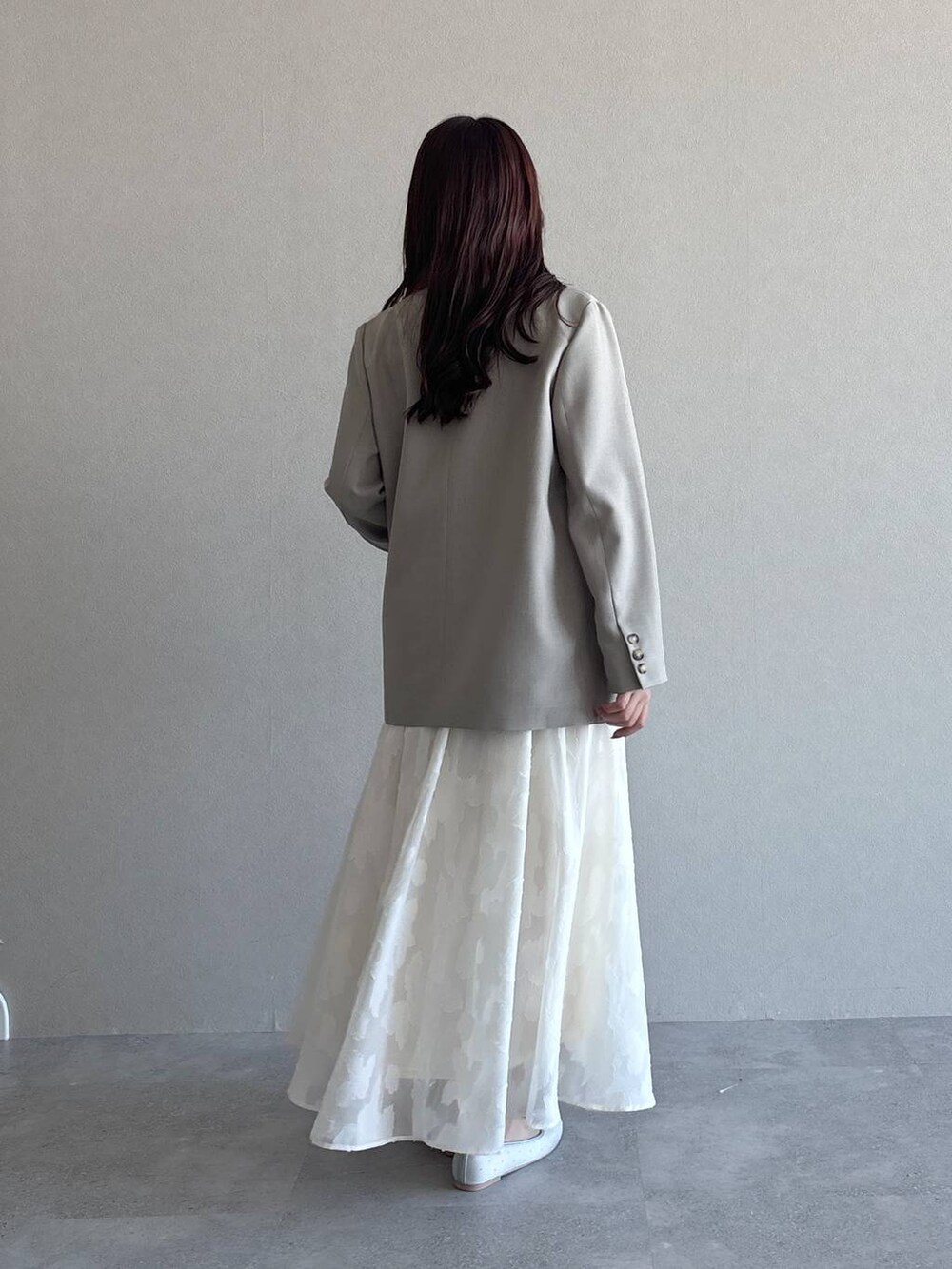 ベージュ系のテーラードジャケット、シルバー系のバレエシューズ、ホワイト系のワンピースを着用したレディースの冬コーディネートの3枚目の写真