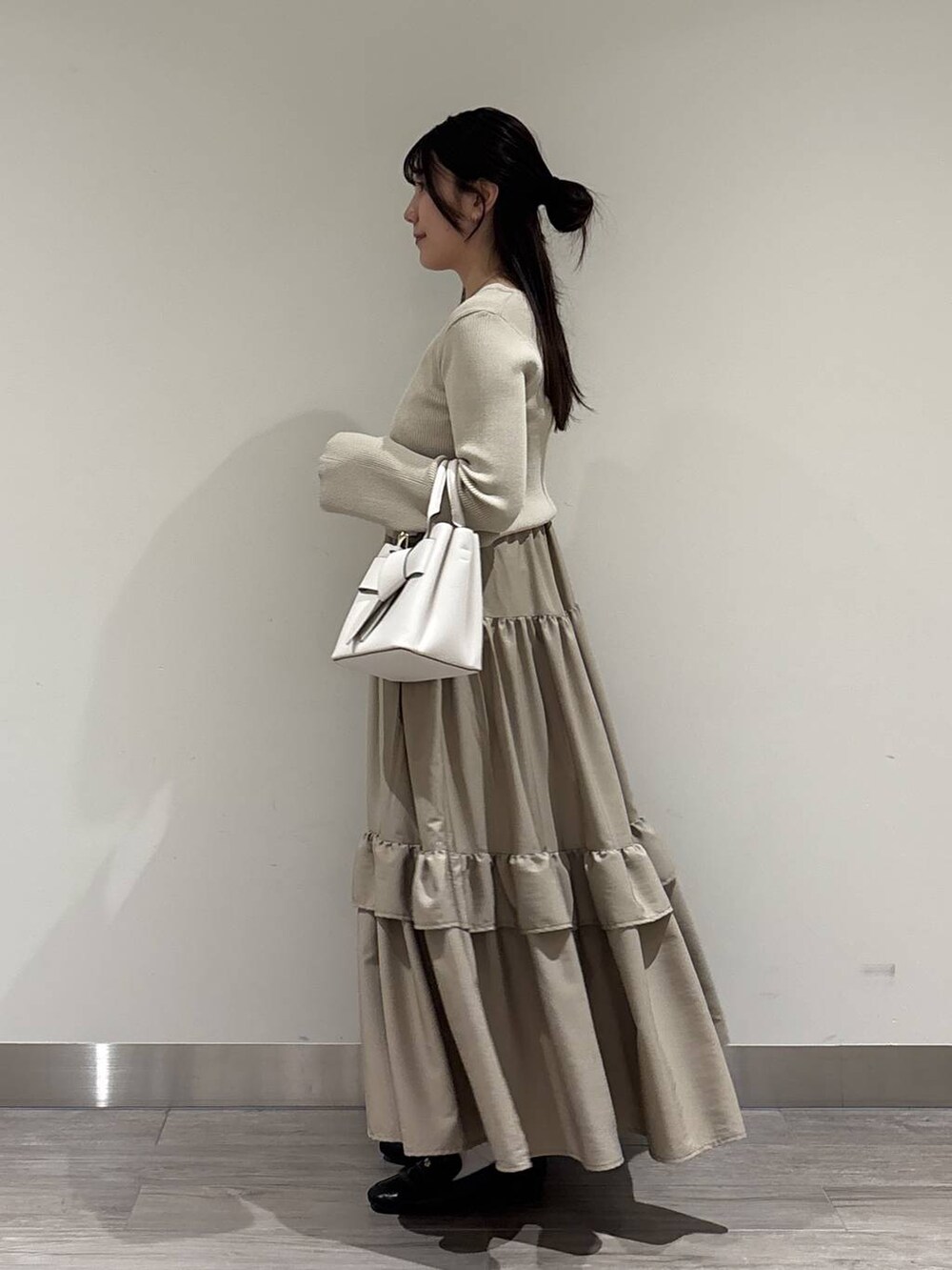 ホワイト系のショルダーバッグ、ブラック系のローファー、ベージュ系のワンピースを着用したレディースの冬コーディネートの2枚目の写真