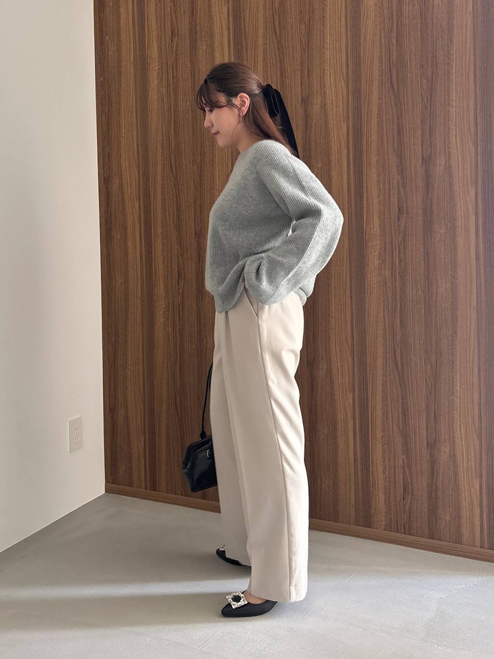 ブラック系のパンプス、ブルー系のニット/セーター、ブラック系のハンドバッグを着用したレディースの冬コーディネートの2枚目の写真