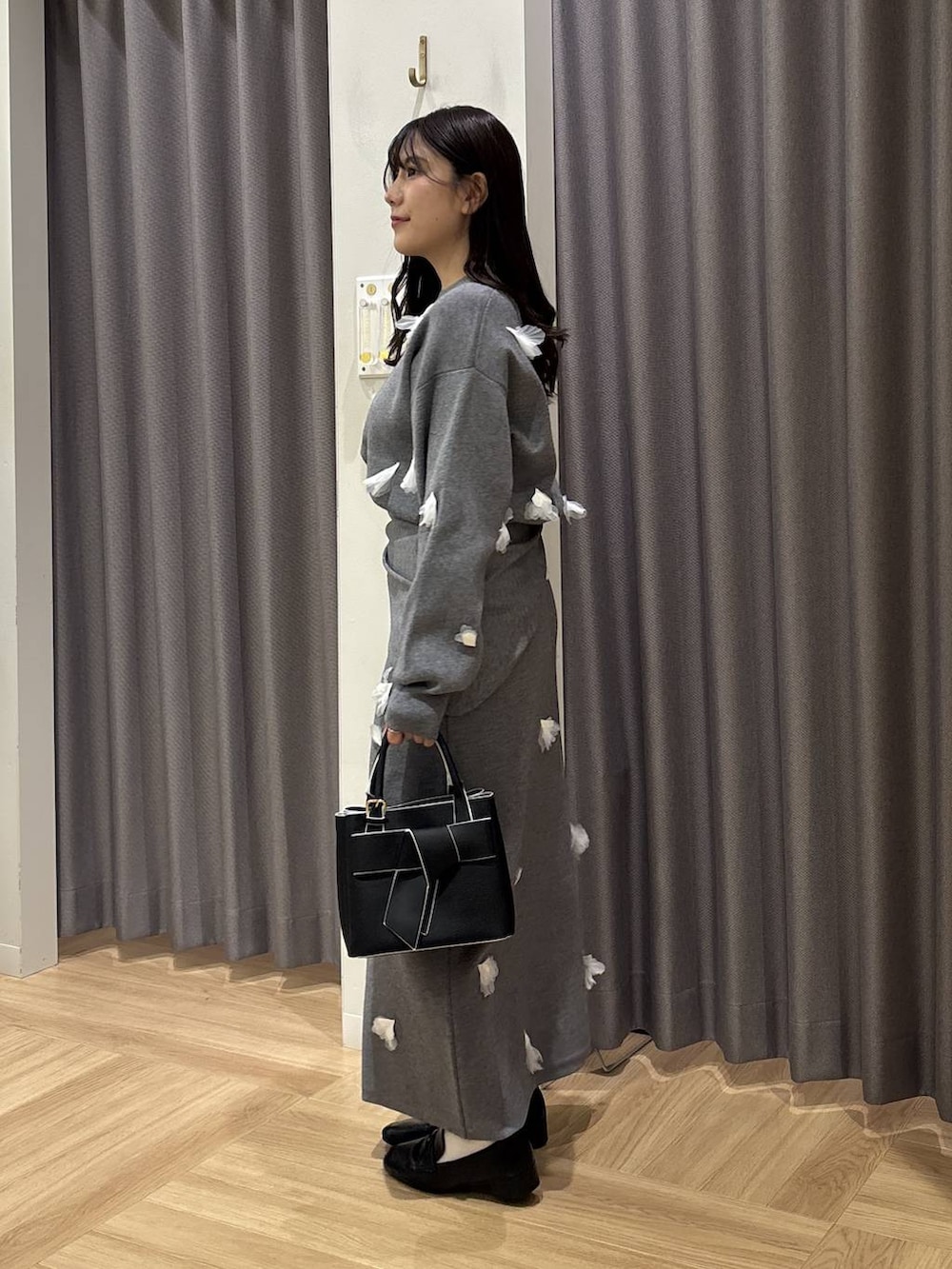 ブラック系のショルダーバッグ、ブラック系のローファー、グレー系のニット/セーターを着用したレディースの冬コーディネートの2枚目の写真