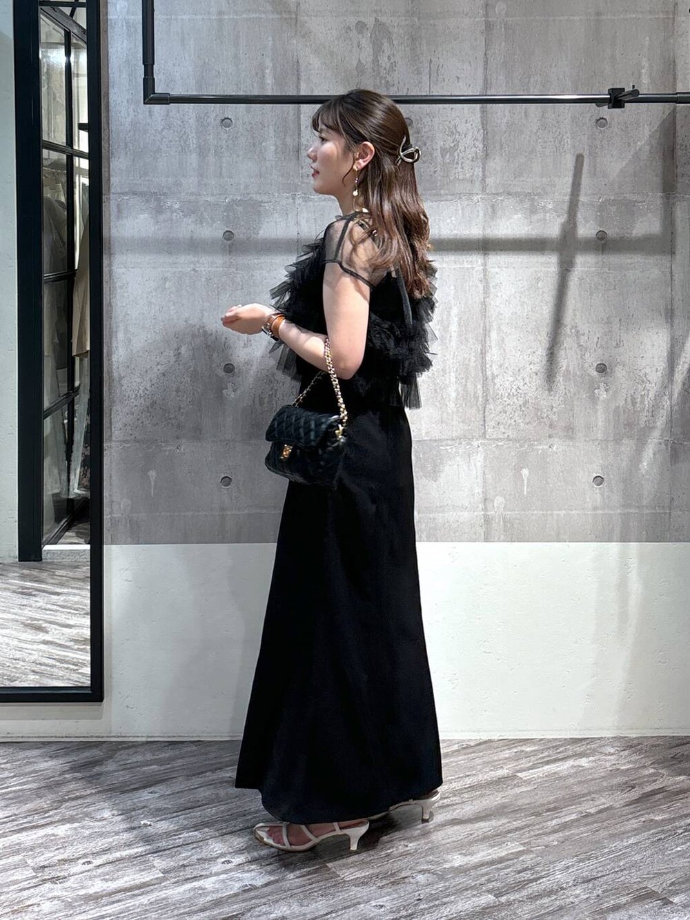 ブラック系のドレス、ブラック系のショルダーバッグ、ホワイト系のサンダルを着用したレディースの春コーディネートの3枚目の写真