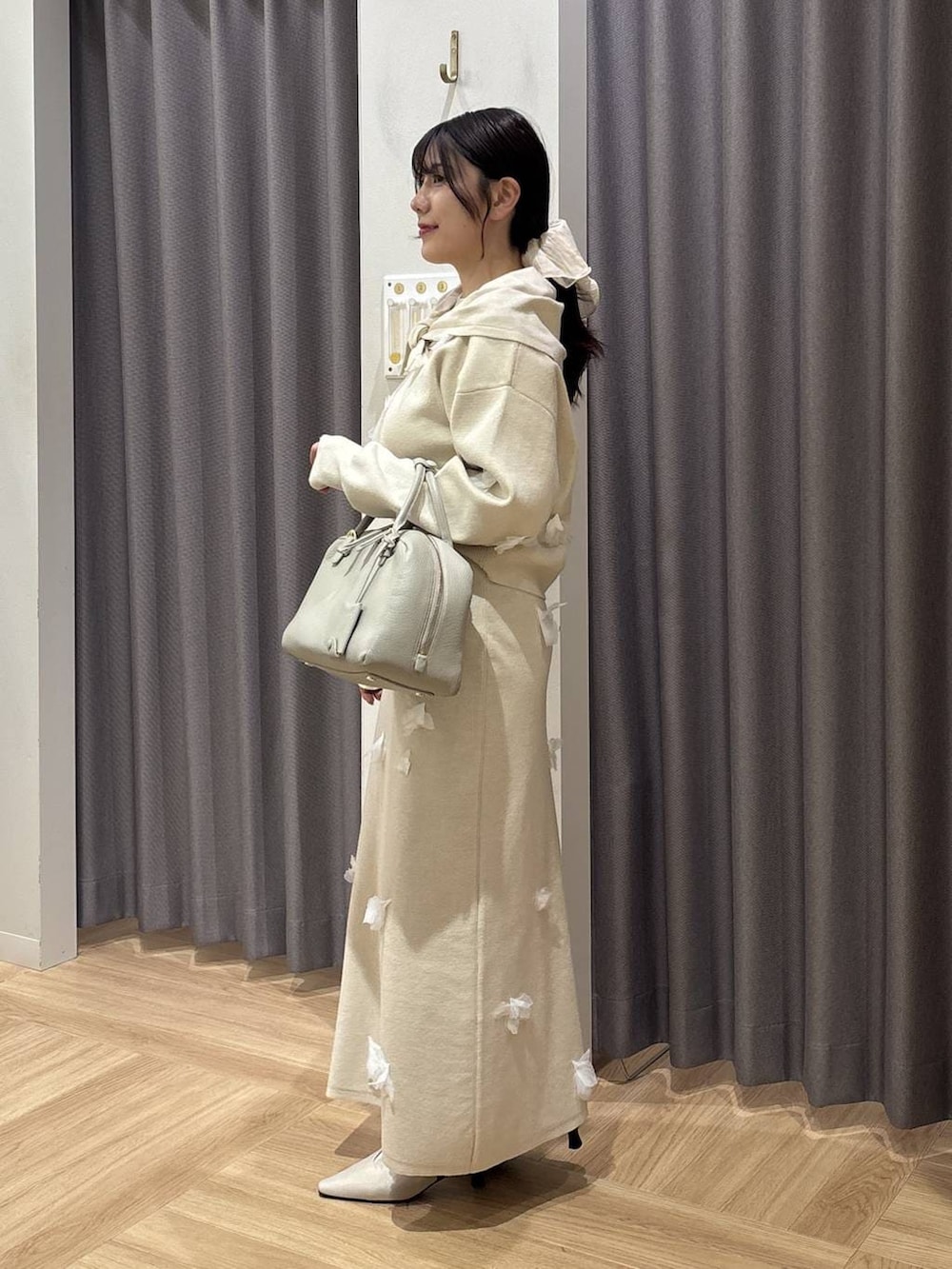 ベージュ系のハンドバッグ、ホワイト系のニット/セーター、ホワイト系のスカートを着用したレディースの冬コーディネートの2枚目の写真