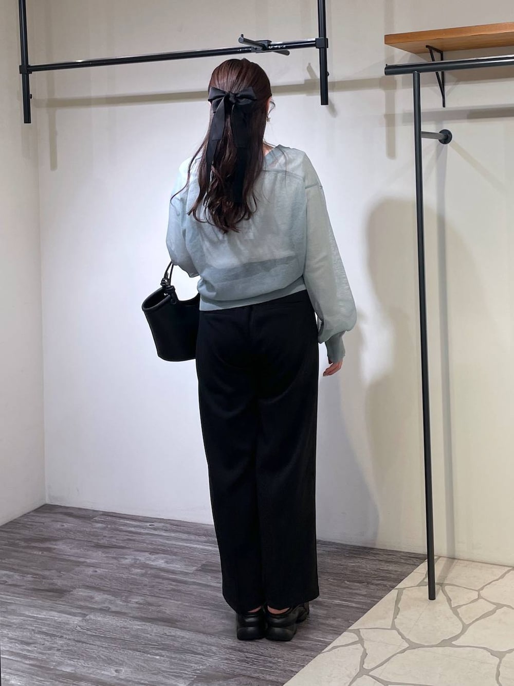 ブラック系のハンドバッグ、ブラック系のスラックス、ホワイト系のTシャツ/カットソーを着用したレディースの春コーディネートの3枚目の写真