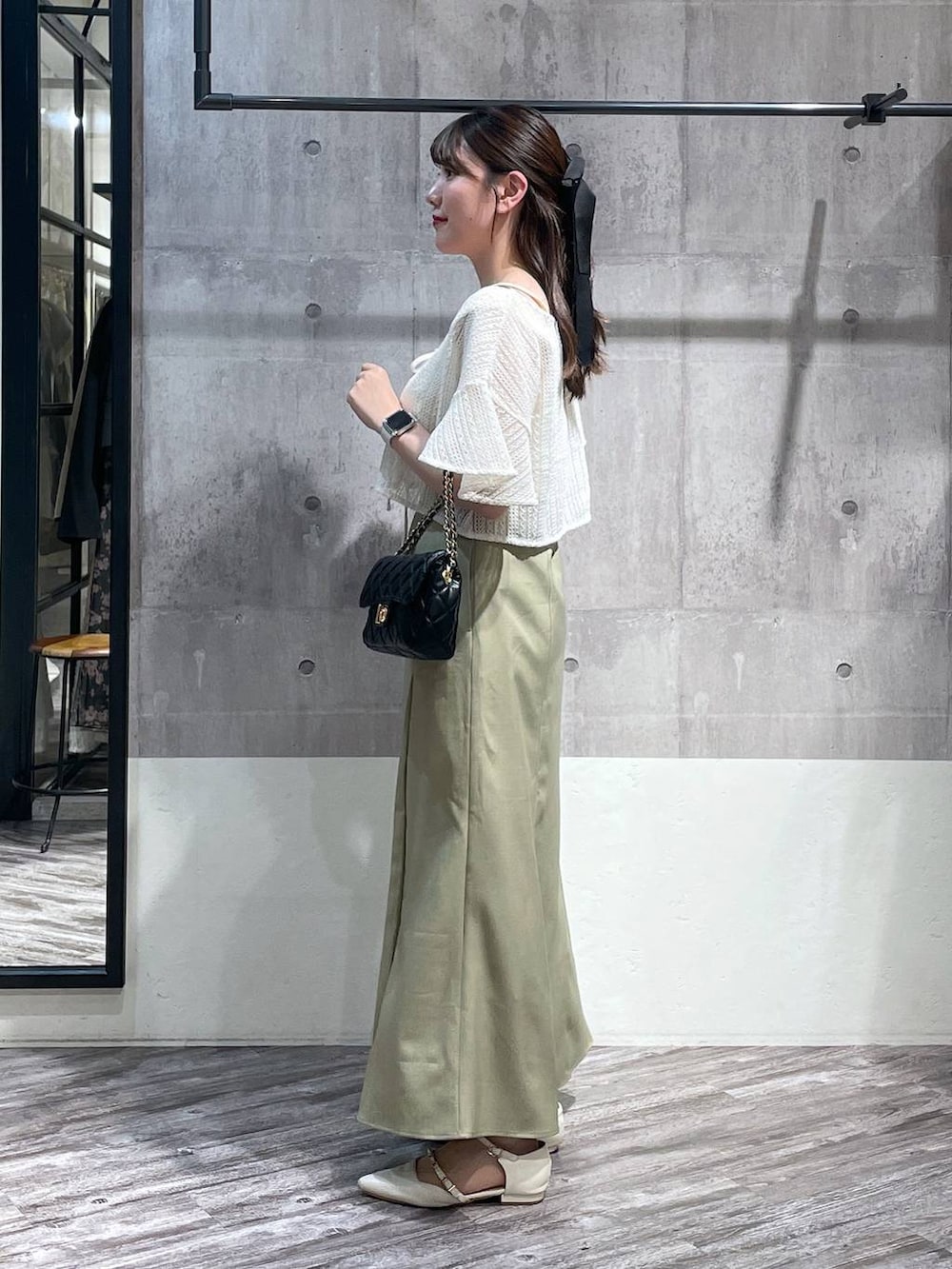 グリーン系のスカート、ホワイト系のカーディガン/ボレロ、ブラック系のショルダーバッグを着用したレディースの春コーディネートの2枚目の写真