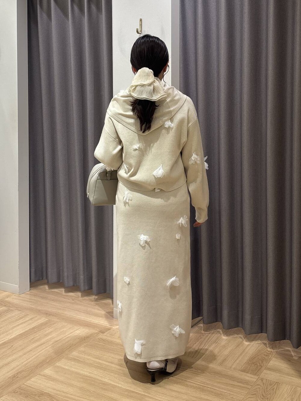 ベージュ系のハンドバッグ、ホワイト系のニット/セーター、ホワイト系のスカートを着用したレディースの冬コーディネートの3枚目の写真