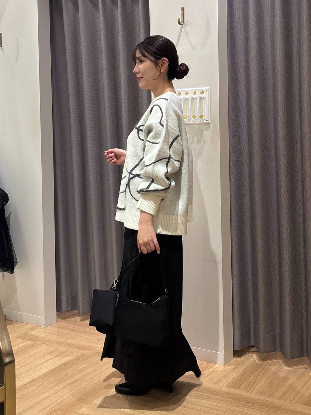 ホワイト系のニット/セーター、ブラック系のスカート、ブラック系のブーツを着用したレディースの秋コーディネートの2枚目の写真