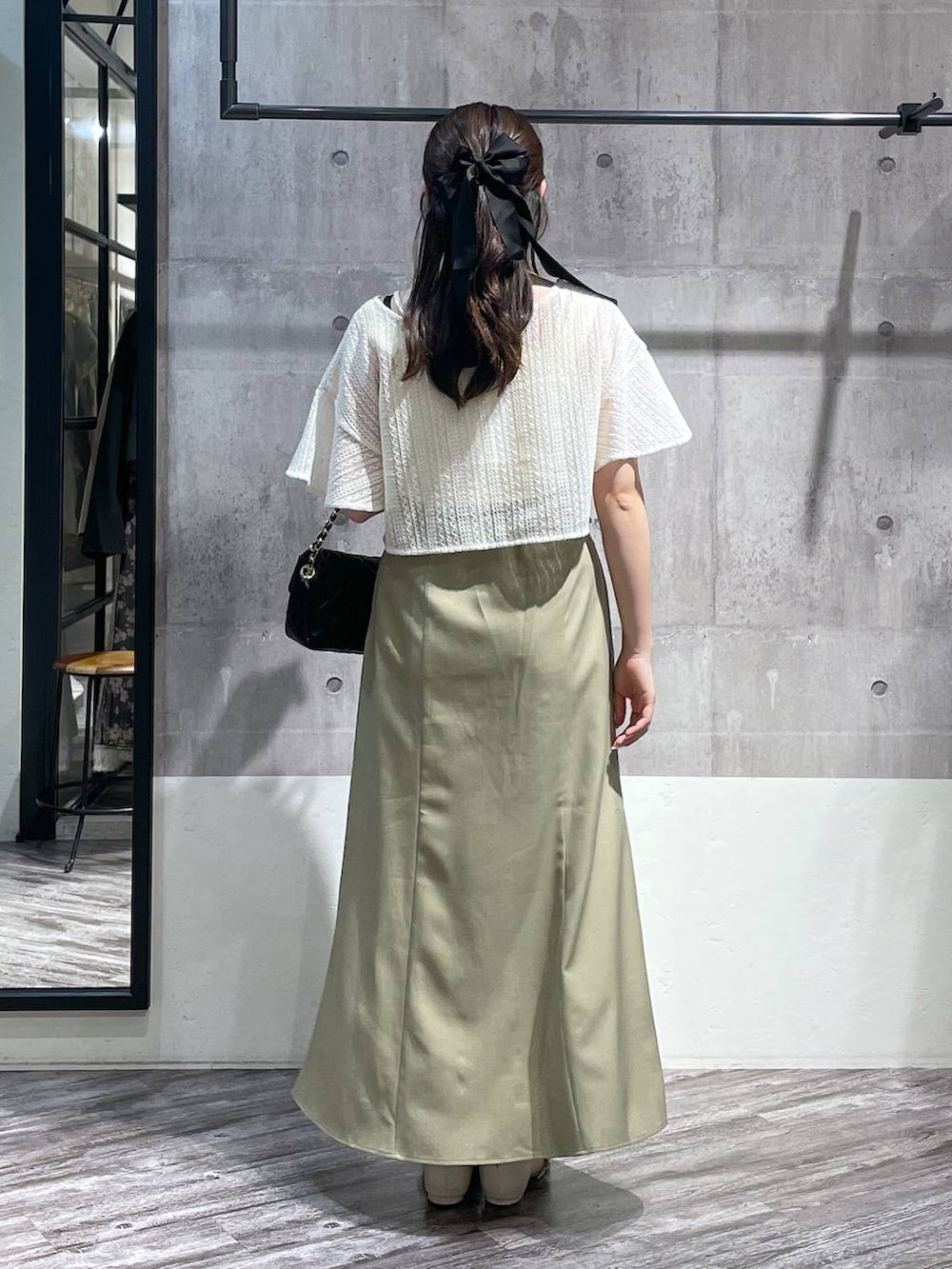 グリーン系のスカート、ホワイト系のカーディガン/ボレロ、ブラック系のショルダーバッグを着用したレディースの春コーディネートの3枚目の写真