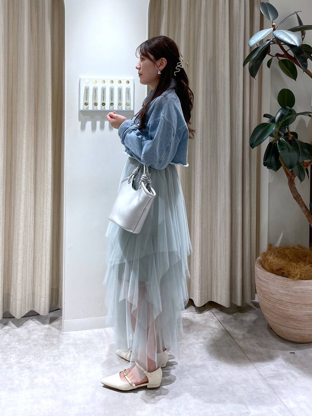 シルバー系のハンドバッグ、グリーン系のスカート、ホワイト系のパンプスを着用したレディースの春コーディネートの2枚目の写真