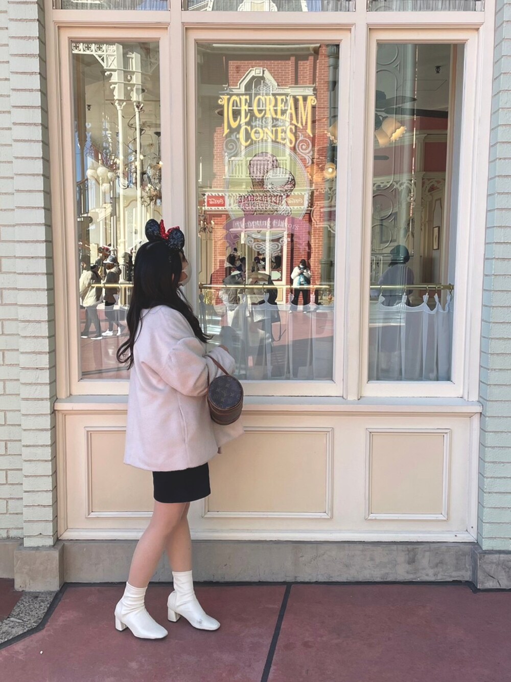 ホワイト系のニット/セーター、ホワイト系のその他アウター、ブラウン系のハンドバッグを着用したレディースの冬コーディネートの2枚目の写真