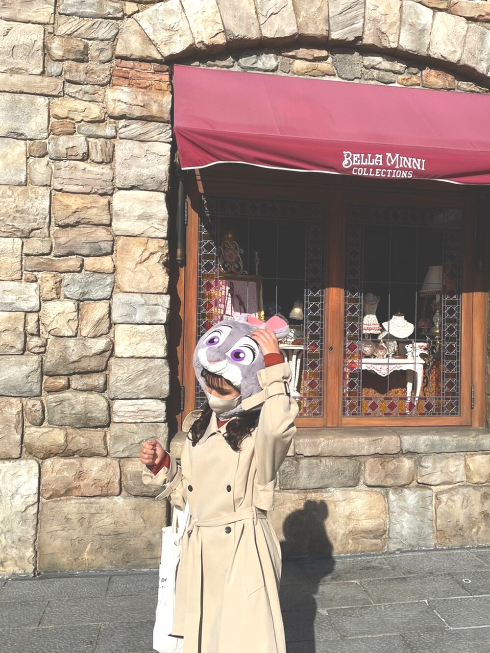 ベージュ系のトレンチコート、ブルー系のデニムパンツ、ブラウン系のニット/セーターを着用したレディースの冬コーディネートの2枚目の写真