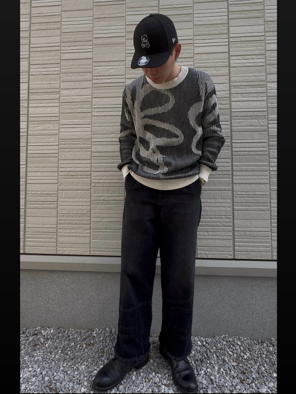 ブラック系のデニムパンツ、ブラック系のニット/セーター、ブラック系のブーツを着用したメンズの春コーディネートの2枚目の写真