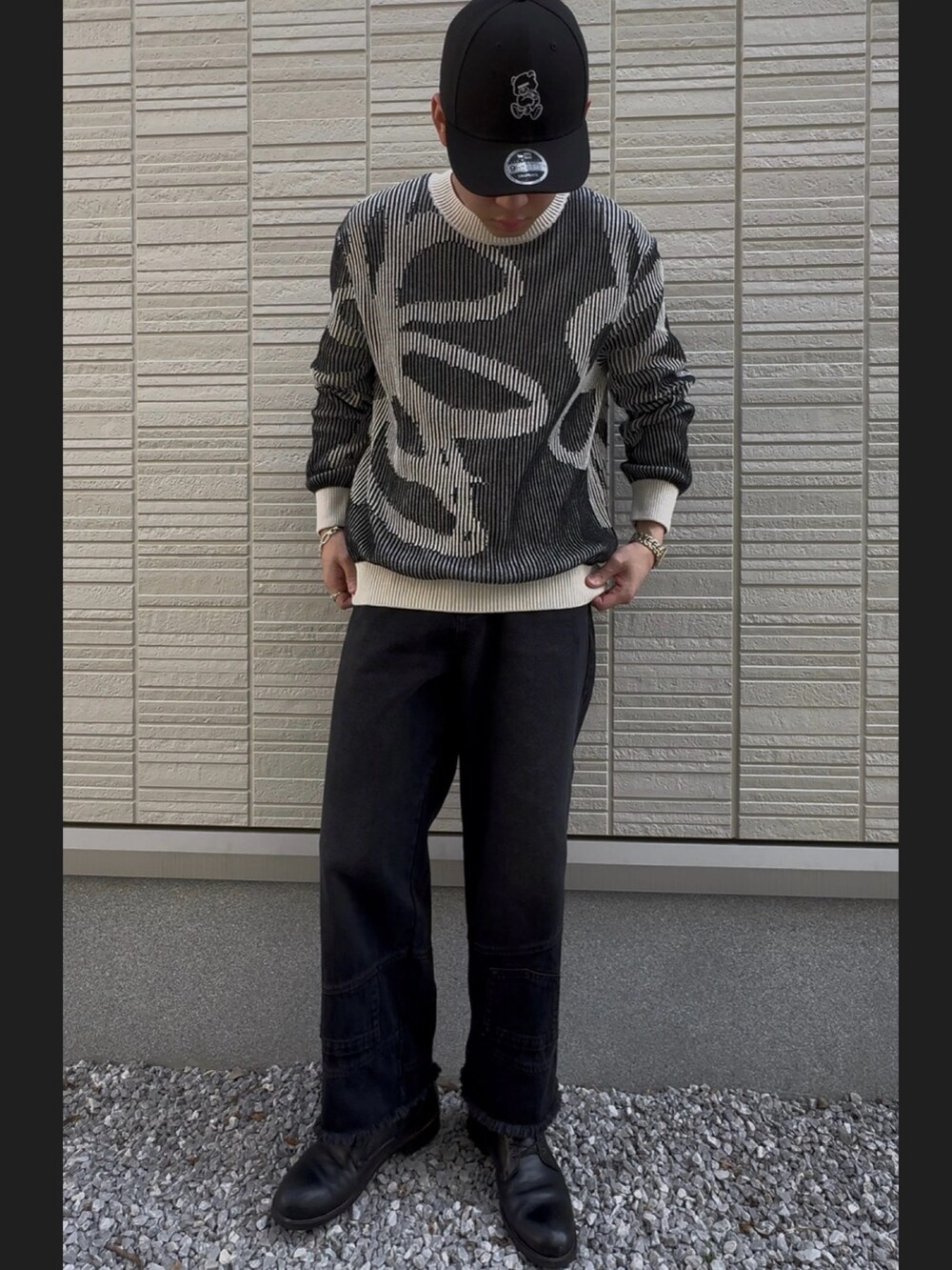 ブラック系のデニムパンツ、ブラック系のニット/セーター、ブラック系のブーツを着用したメンズの春コーディネートの3枚目の写真