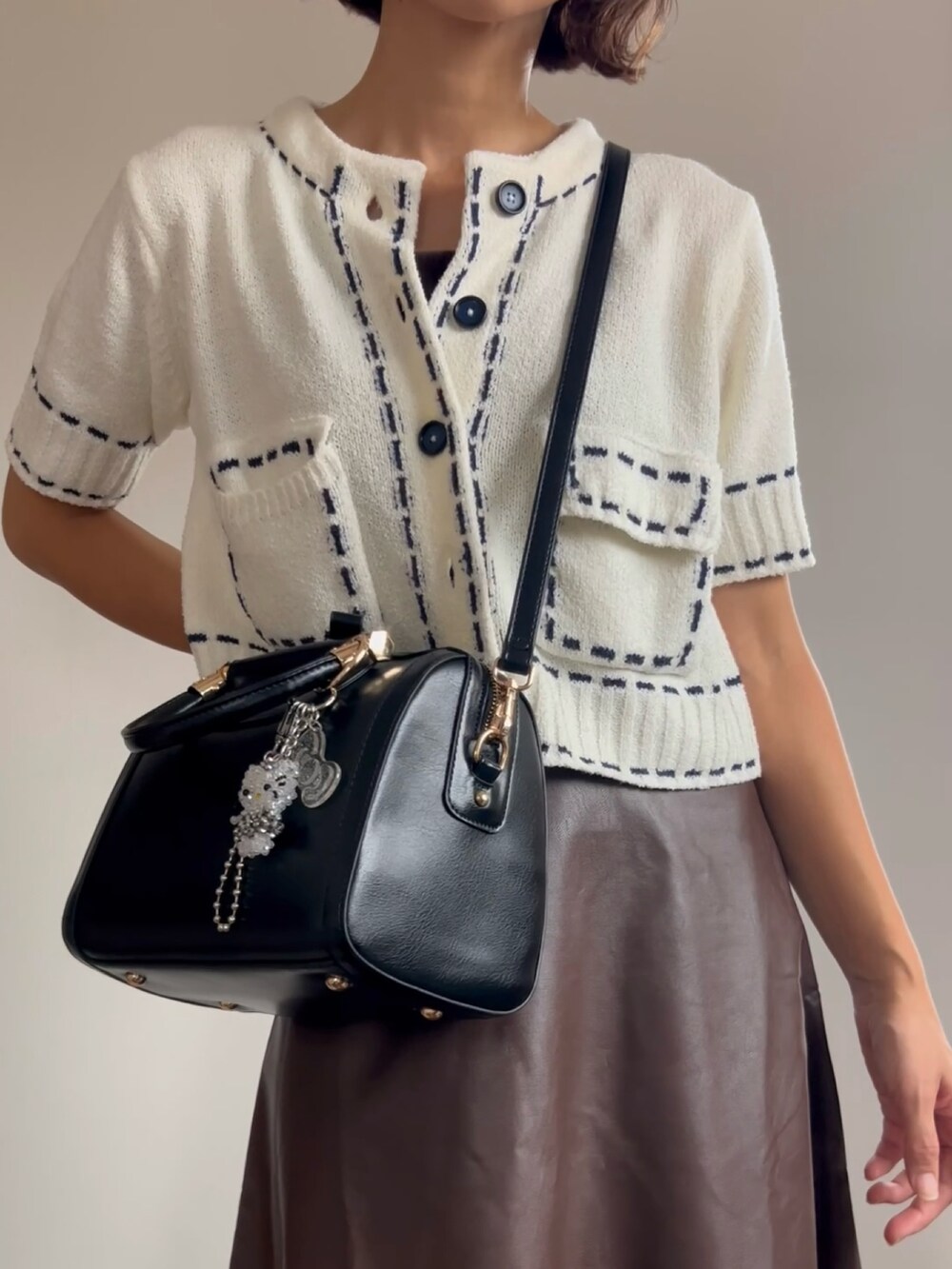 ブラック系のボストンバッグ、ブラウン系のスカートを着用したレディースの夏コーディネートの2枚目の写真