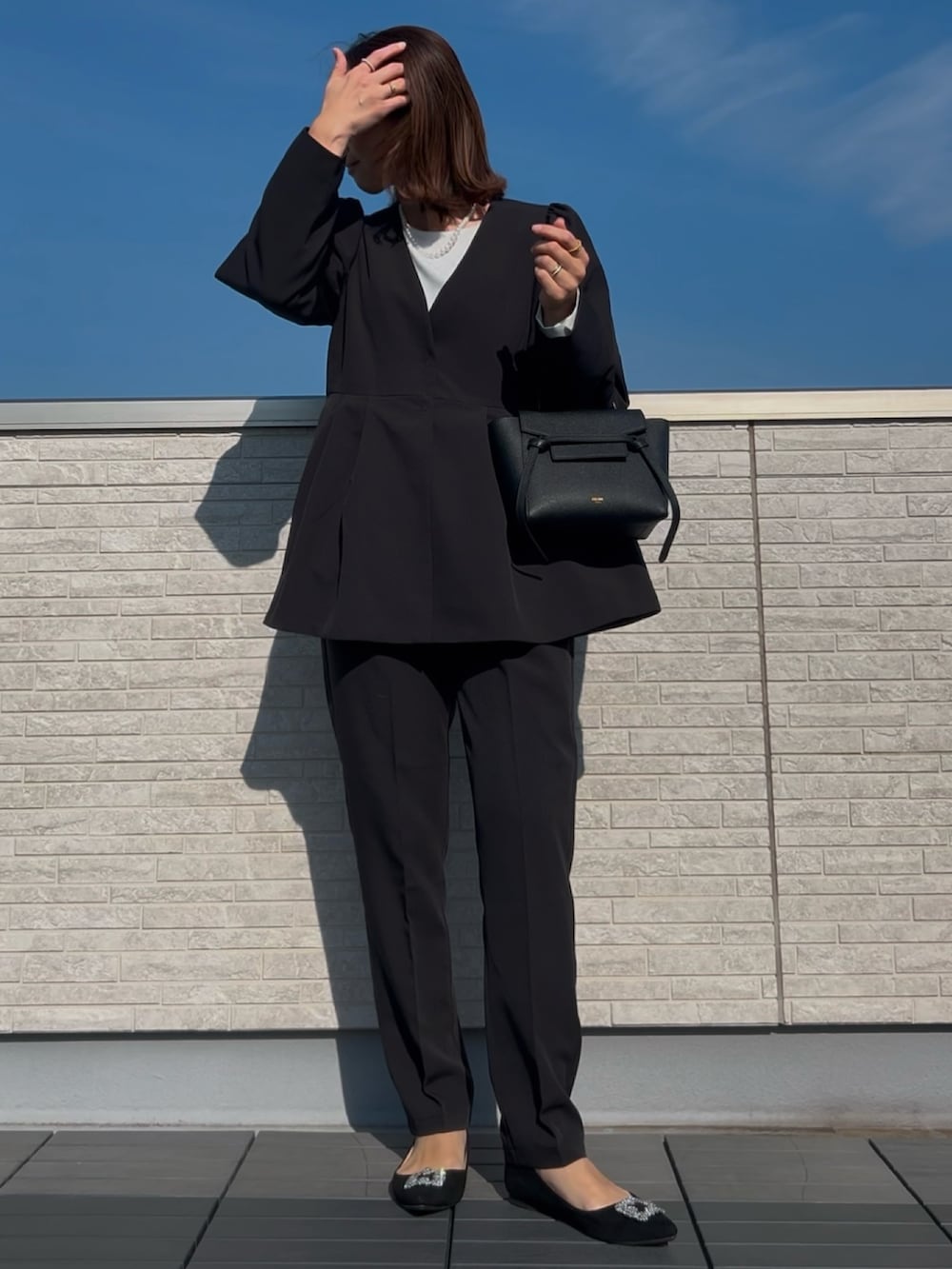 ブラック系のスーツセット、ブラック系のパンプスを着用したレディースの冬コーディネートの2枚目の写真
