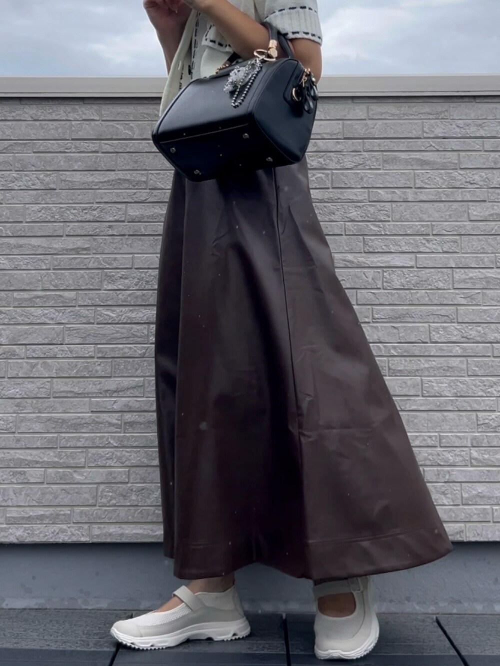 ブラック系のボストンバッグ、ブラウン系のスカートを着用したレディースの夏コーディネートの3枚目の写真