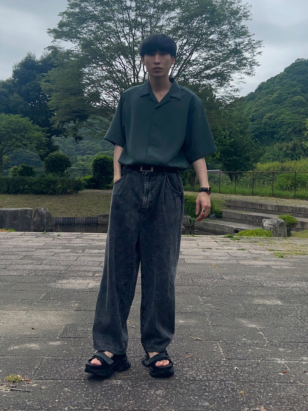 グレー系のデニムパンツ、ブラック系のサンダル、ブラック系のカーディガン/ボレロを着用したメンズの春コーディネートの2枚目の写真