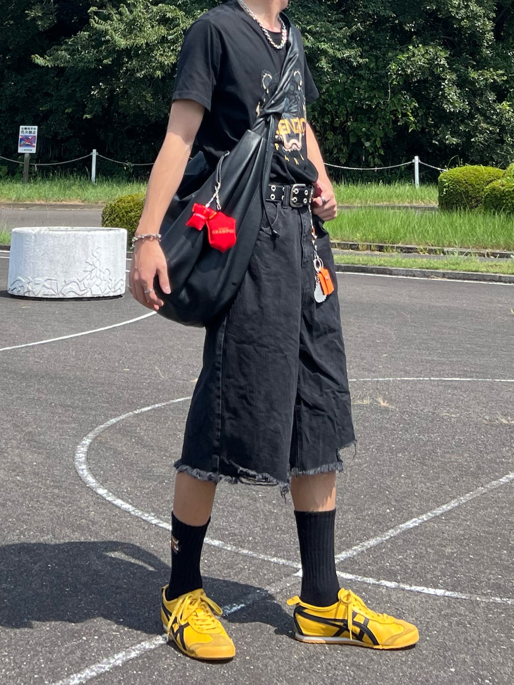 イエロー系のスニーカー、ブラック系のデニムパンツ、ブラック系のTシャツ/カットソーを着用したメンズの夏コーディネートの2枚目の写真