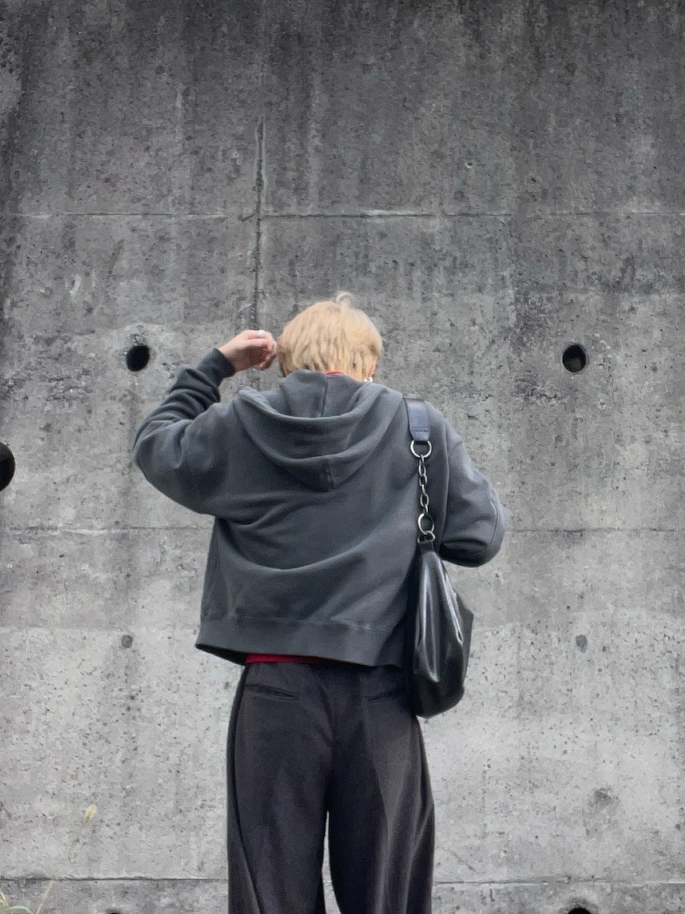 グレー系のパーカー、グレー系のスラックス、グレー系のスニーカーを着用したメンズの秋コーディネートの2枚目の写真