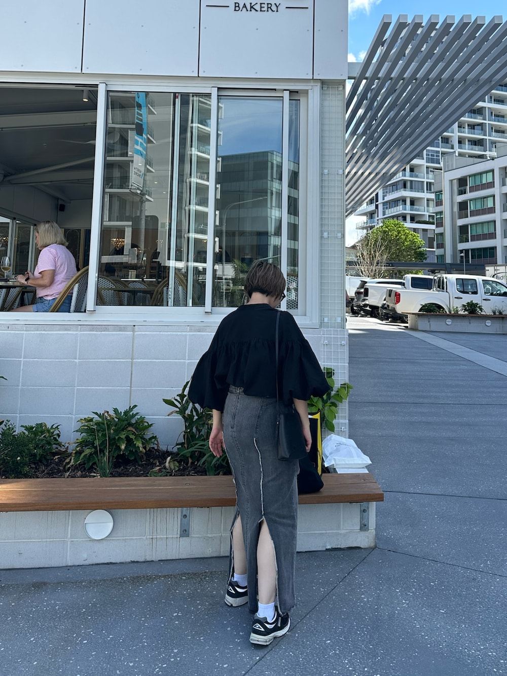 ブラック系のシャツ/ブラウス、ブラック系のデニムスカート、ブラック系のトートバッグを着用したレディースの春コーディネートの2枚目の写真