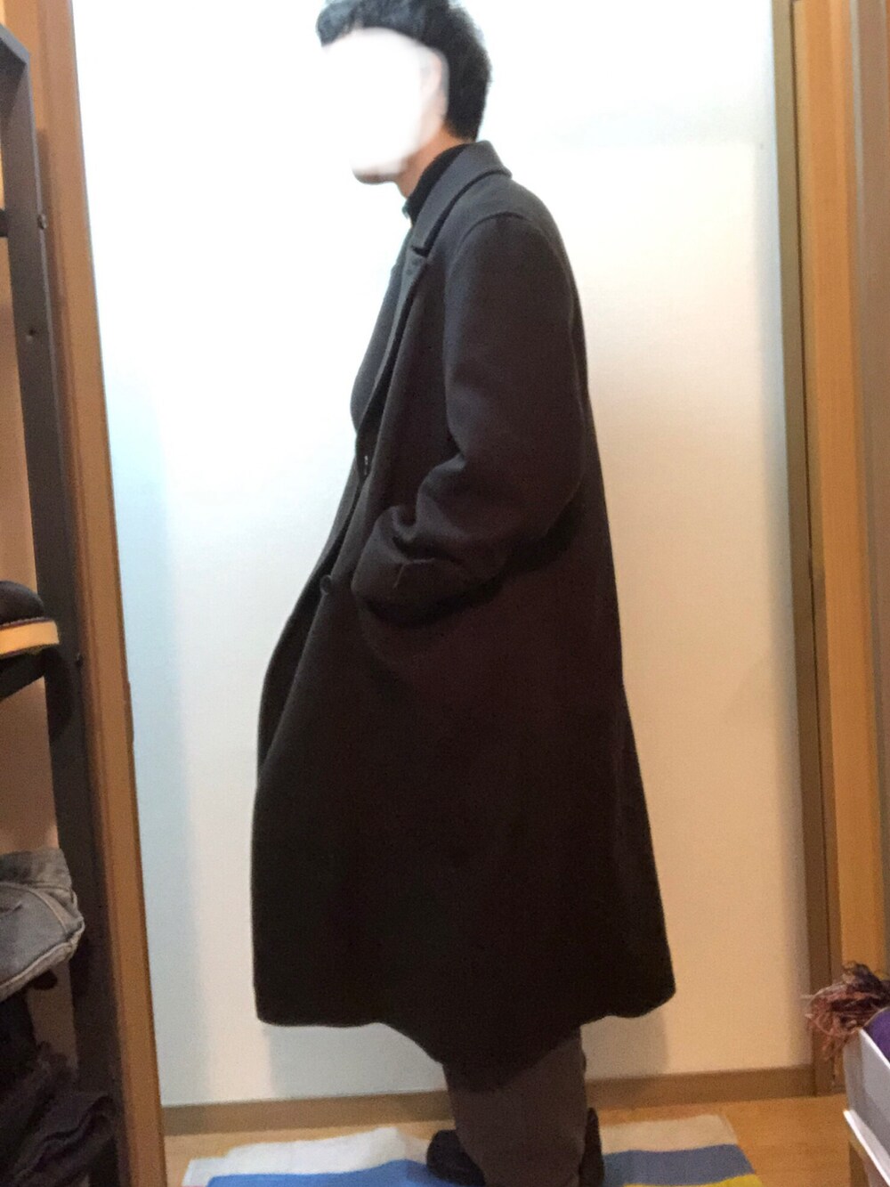 ブラック系のチェスターコート、ブラック系のニット/セーター、グレー系のその他パンツを着用したメンズの冬コーディネートの2枚目の写真