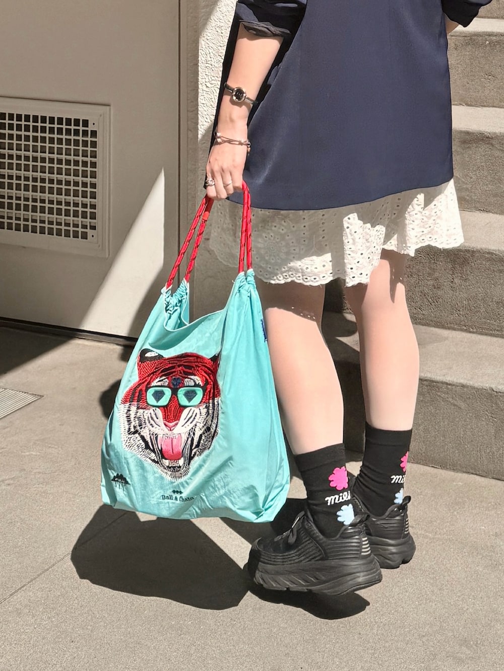 ブルー系のテーラードジャケット、ブルー系のエコバッグ/サブバッグ、ホワイト系のチュニックを着用したレディースの春コーディネートの2枚目の写真