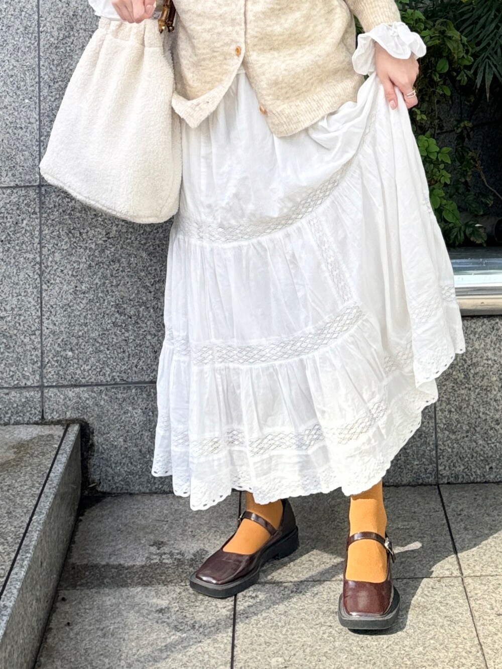 ベージュ系のニット/セーター、ホワイト系のスカート、ブラウン系のパンプスを着用したレディースの秋コーディネートの2枚目の写真