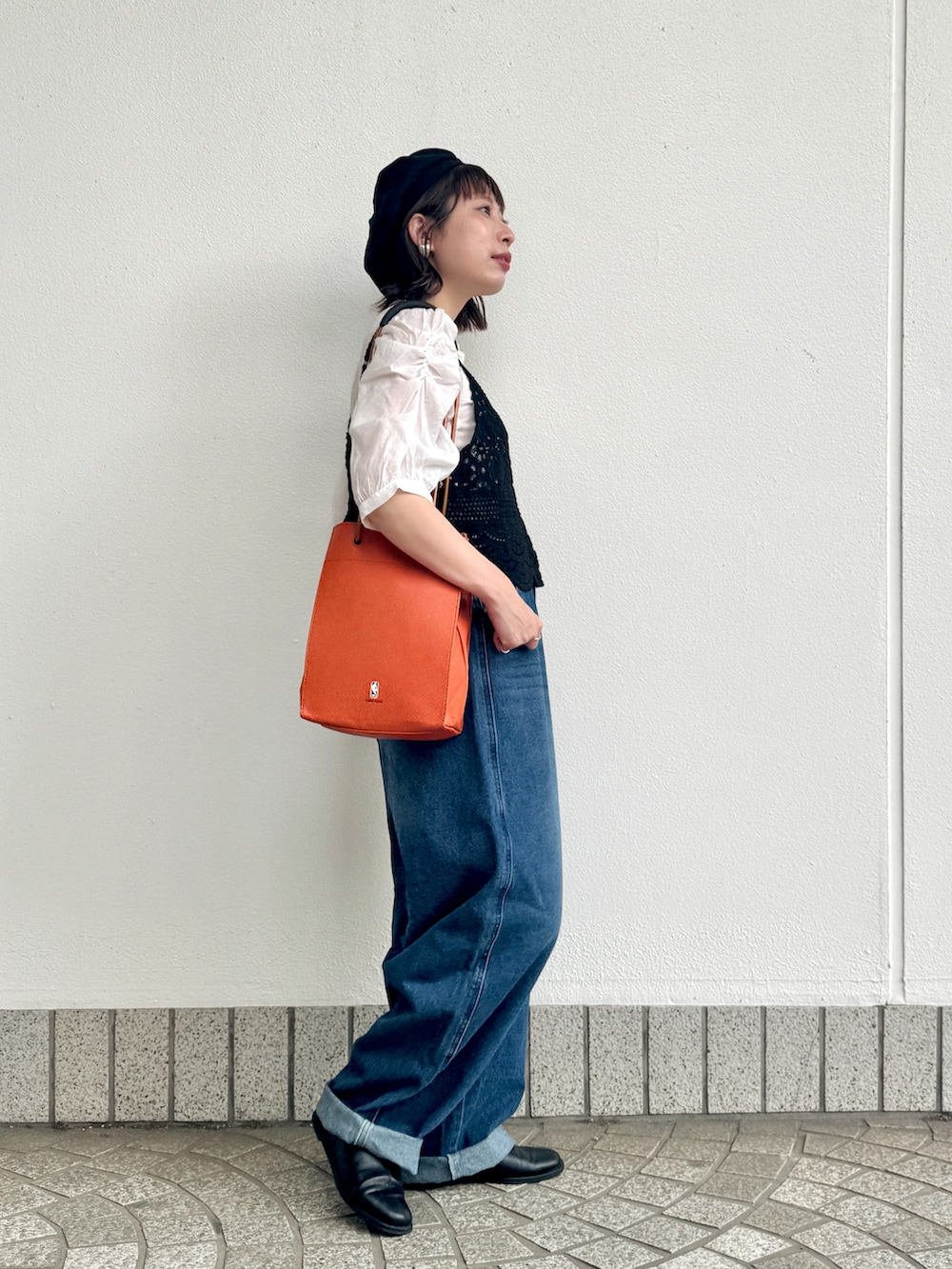 ブラック系のベスト、ブルー系のデニムパンツ、ブラック系のパンプスを着用したレディースの春コーディネートの2枚目の写真