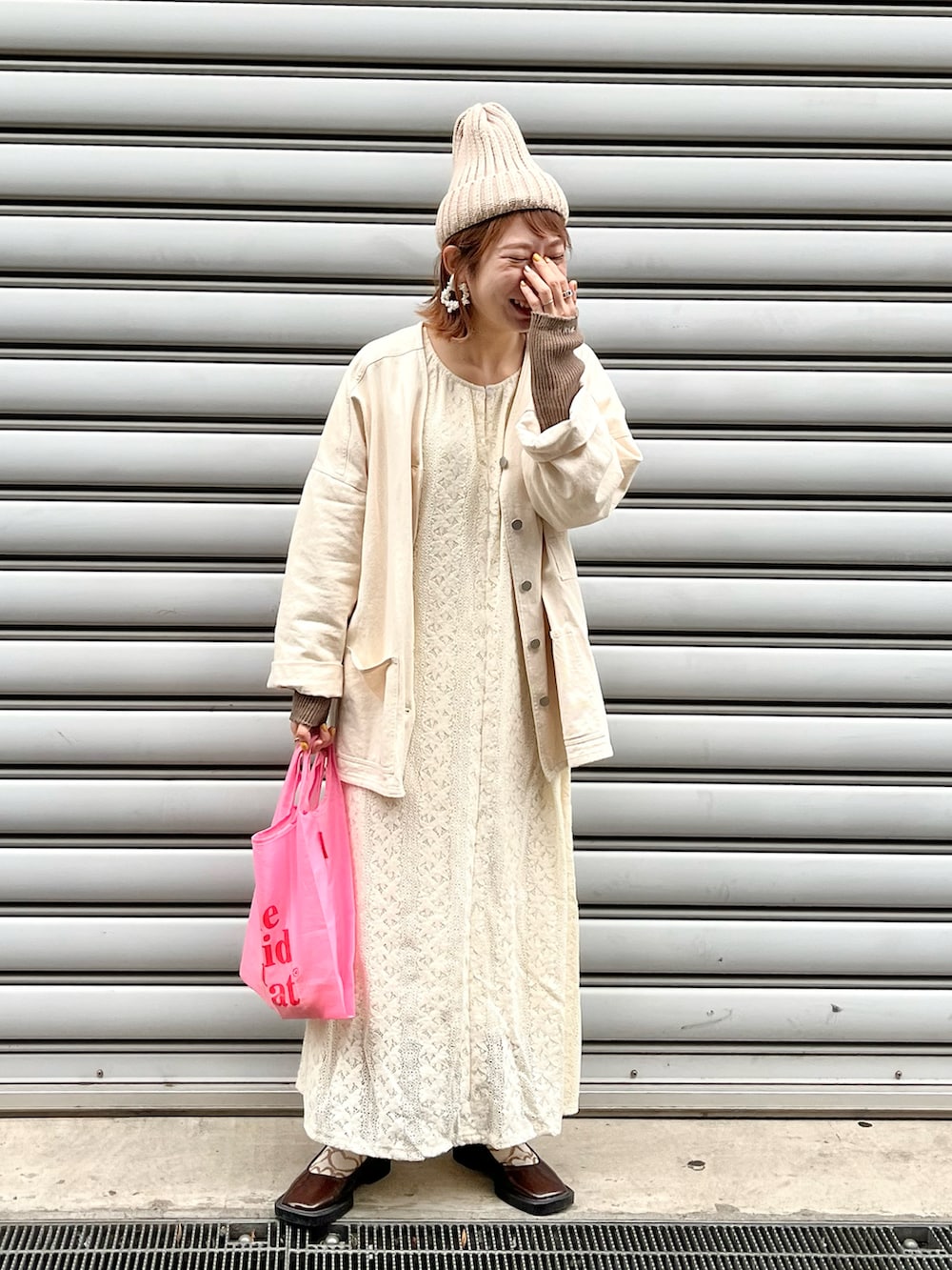 ホワイト系のノーカラーコート、ホワイト系のワンピース、ブラウン系のパンプスを着用したレディースの冬コーディネートの2枚目の写真