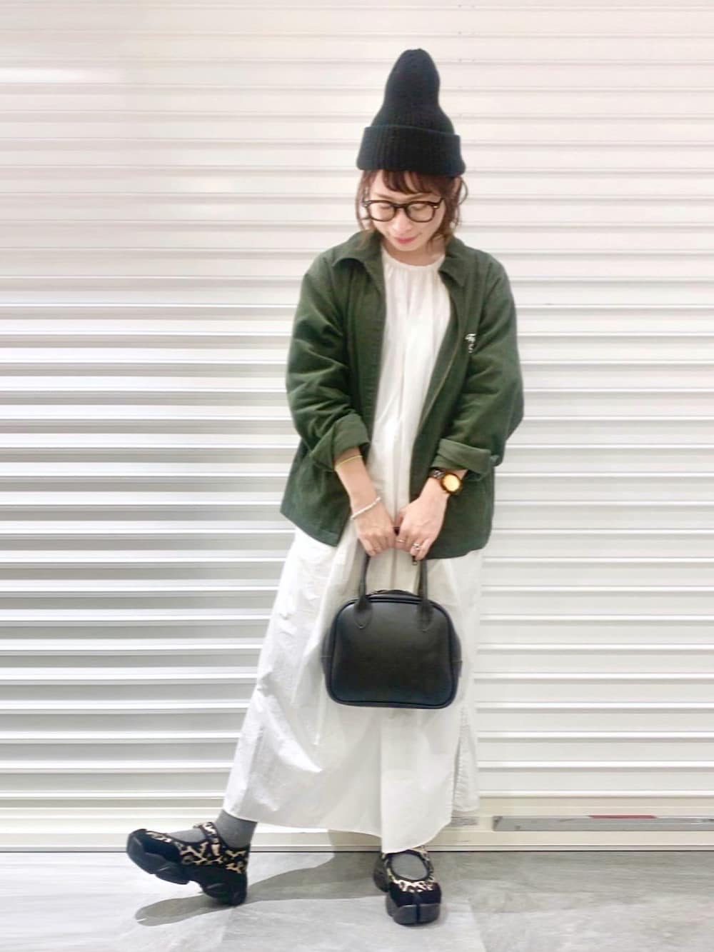 グリーン系のブルゾン、ホワイト系のワンピース、ブラック系のショルダーバッグを着用したレディースの冬コーディネートの2枚目の写真