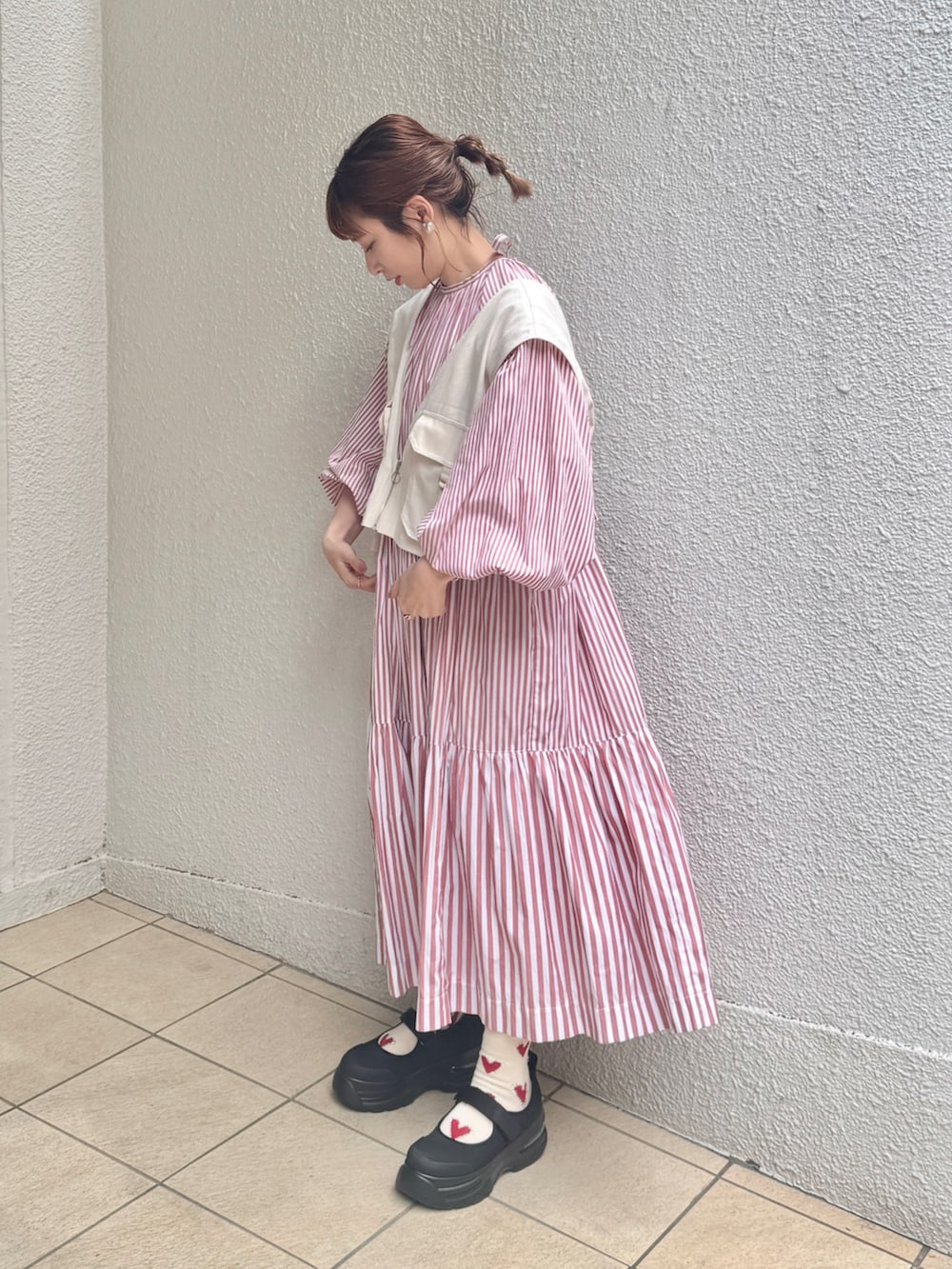 ホワイト系のベスト、ピンク系のワンピース、ブラック系のスニーカーを着用したレディースの春コーディネートの2枚目の写真