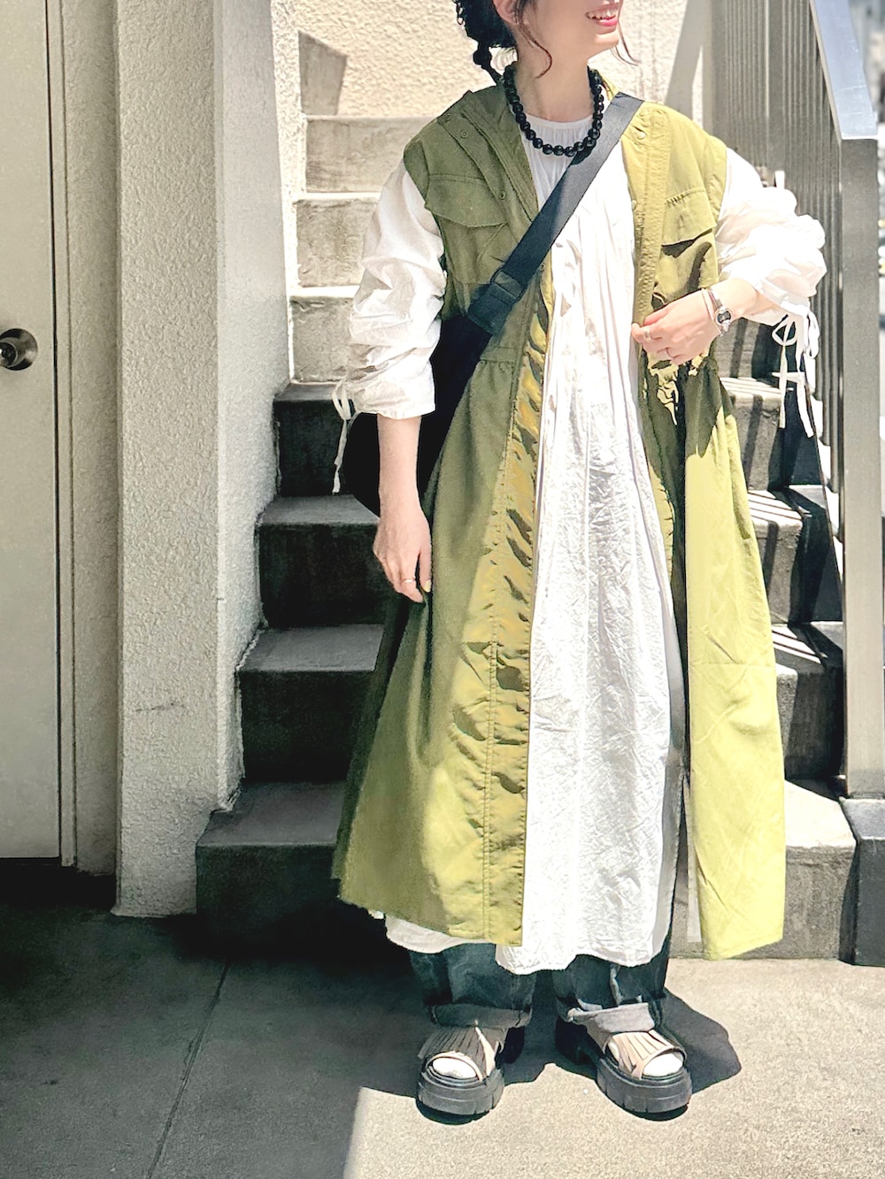 ホワイト系のワンピース、グリーン系のその他アウター、ブラック系のショルダーバッグを着用したレディースの春コーディネートの4枚目の写真