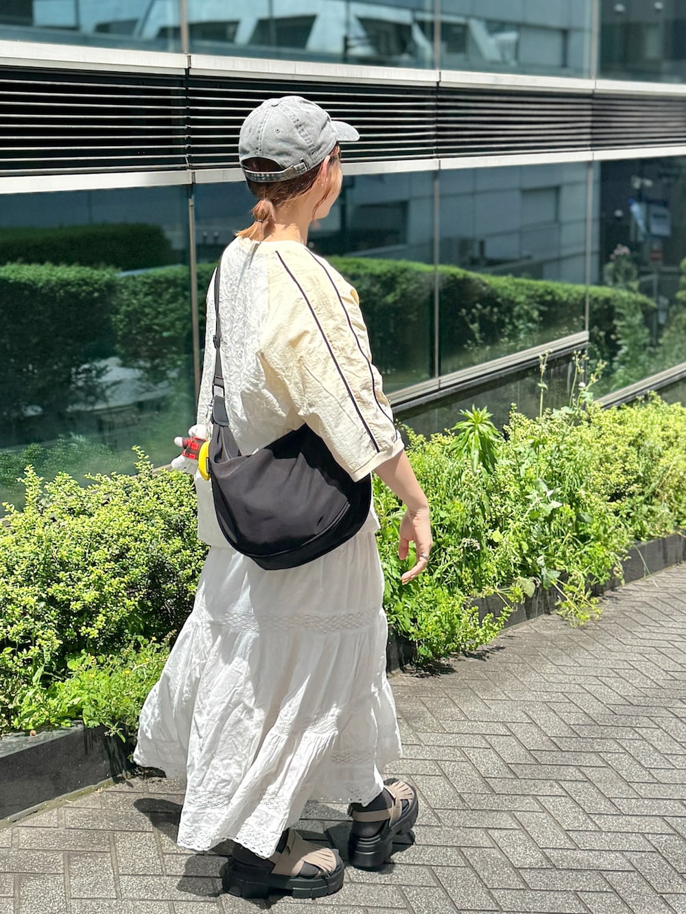 ベージュ系のTシャツ/カットソー、ホワイト系のスカート、ベージュ系のサンダルを着用したレディースの春コーディネートの2枚目の写真