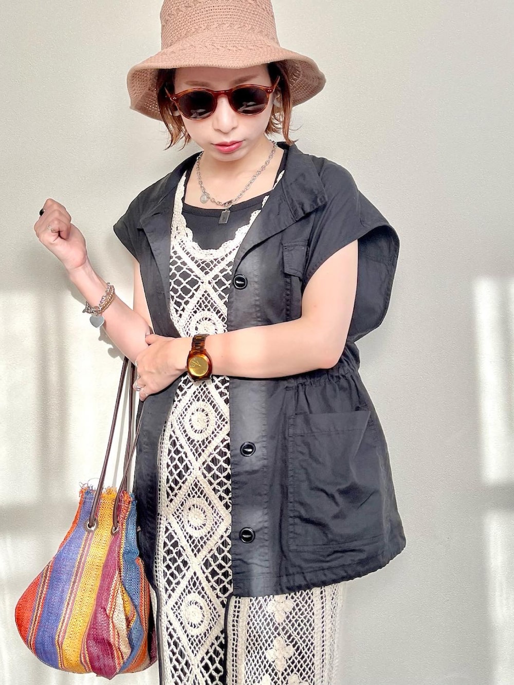 ブラック系のベスト、ホワイト系のワンピース、イエロー系のかごバッグを着用したレディースの夏コーディネートの2枚目の写真