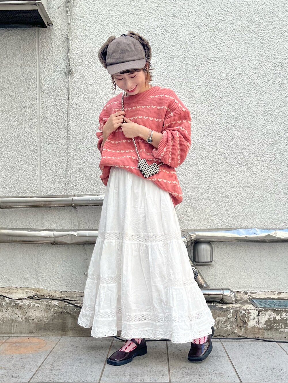 ピンク系のカーディガン/ボレロ、ホワイト系のスカート、ブラウン系のパンプスを着用したレディースの秋コーディネートの2枚目の写真
