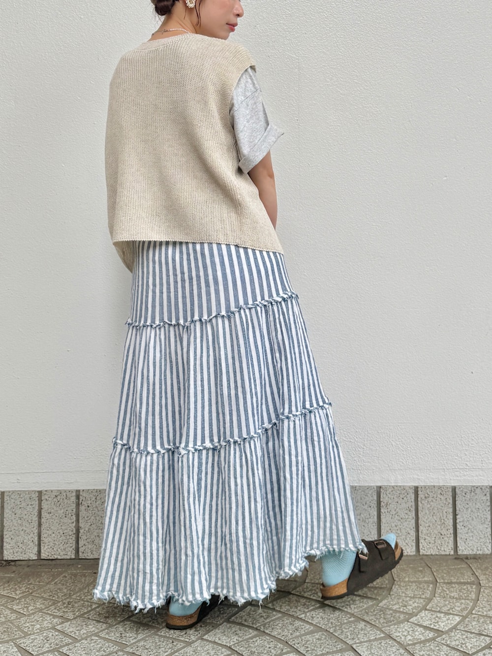 グレー系のTシャツ/カットソー、ホワイト系のベスト、ブラウン系のサンダルを着用したレディースの夏コーディネートの3枚目の写真