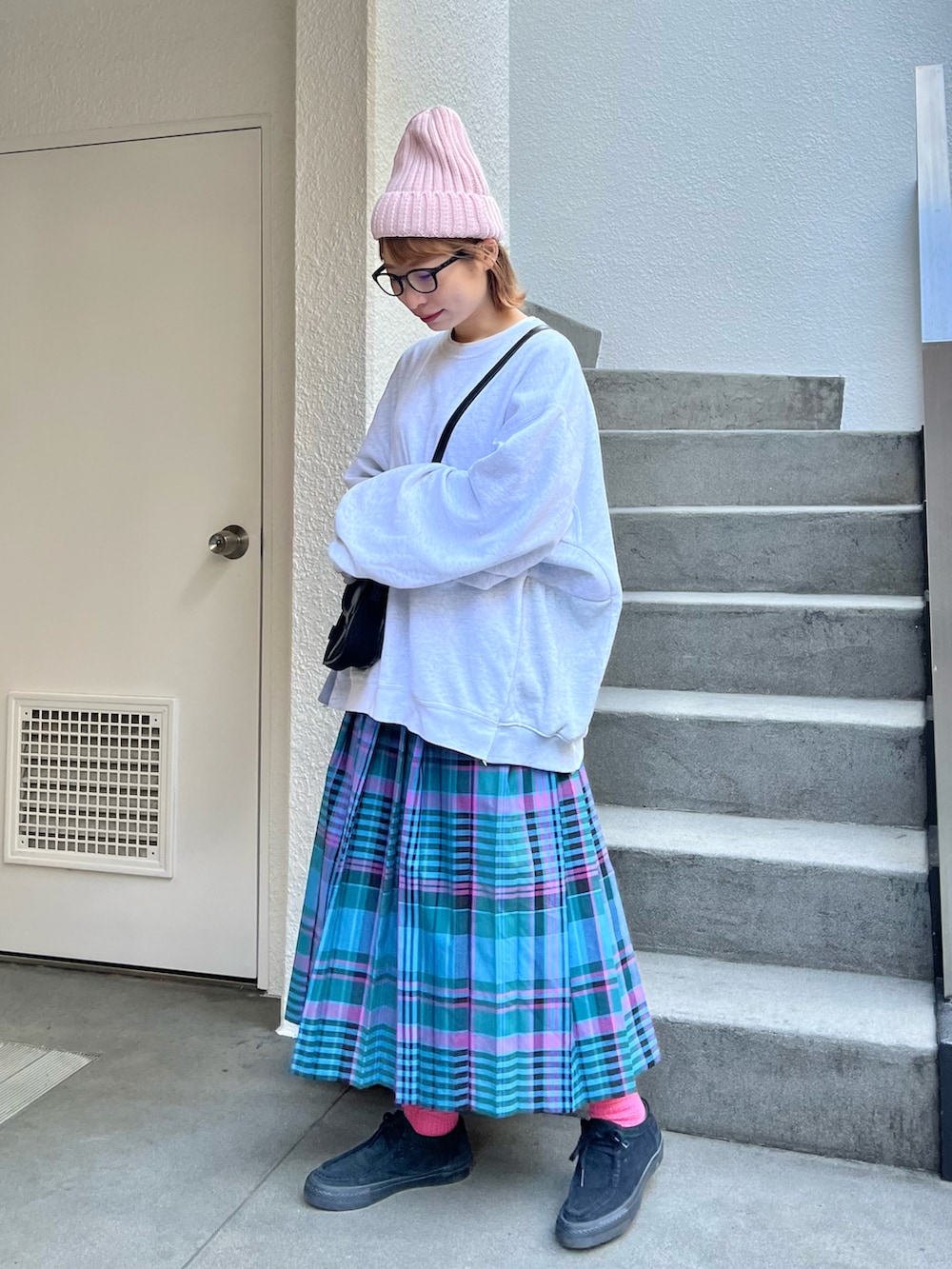 グレー系のスウェット、ブルー系のスカート、ブラック系のスニーカーを着用したレディースの冬コーディネートの2枚目の写真