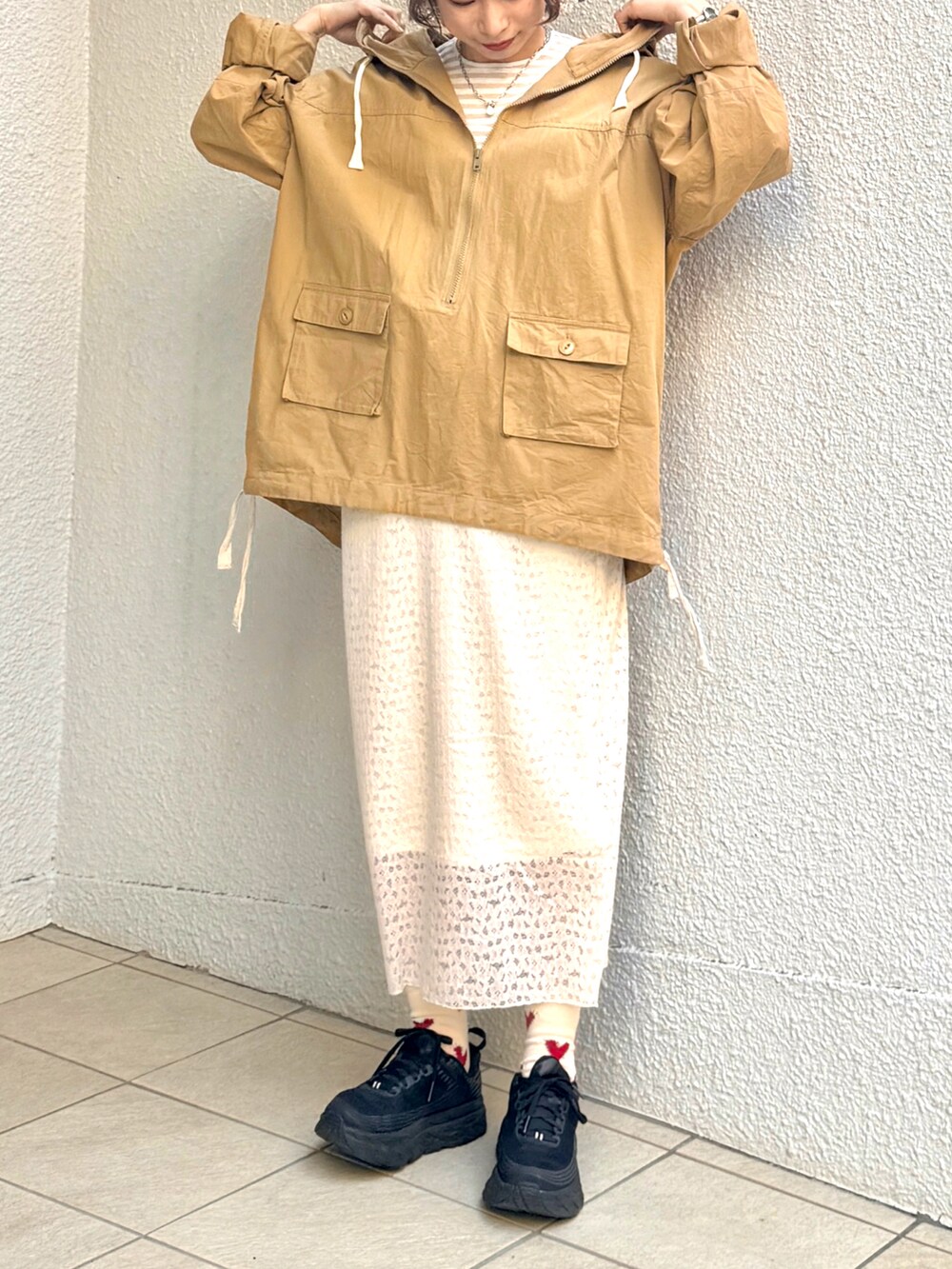 グリーン系のマウンテンパーカー、ホワイト系のスカート、ブラック系のスニーカーを着用したレディースの春コーディネートの3枚目の写真