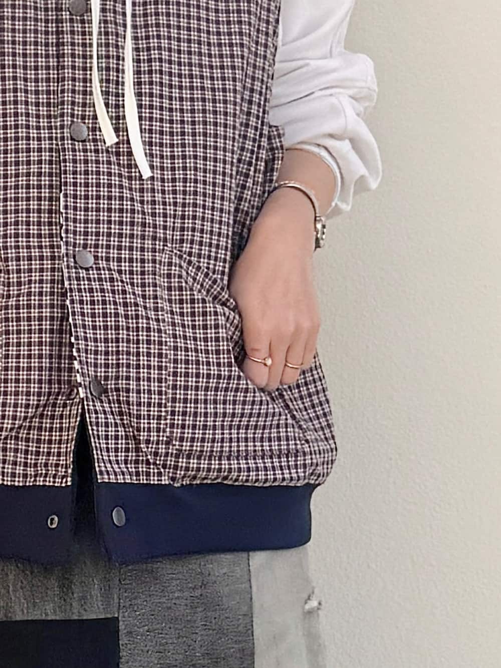 ホワイト系のTシャツ/カットソー、ブルー系のベスト、ブラック系のスニーカーを着用したレディースの春コーディネートの4枚目の写真