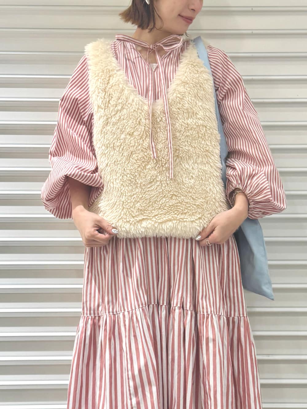 ピンク系のワンピース、ベージュ系のベストを着用したレディースの冬コーディネートの2枚目の写真