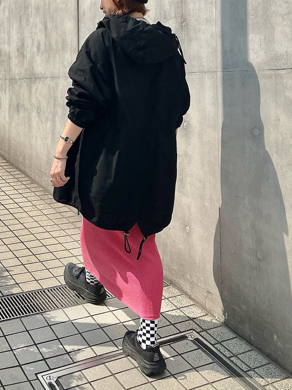 ブラック系のマウンテンパーカー、ピンク系のスカート、ブラック系のスニーカーを着用したレディースの春コーディネートの2枚目の写真