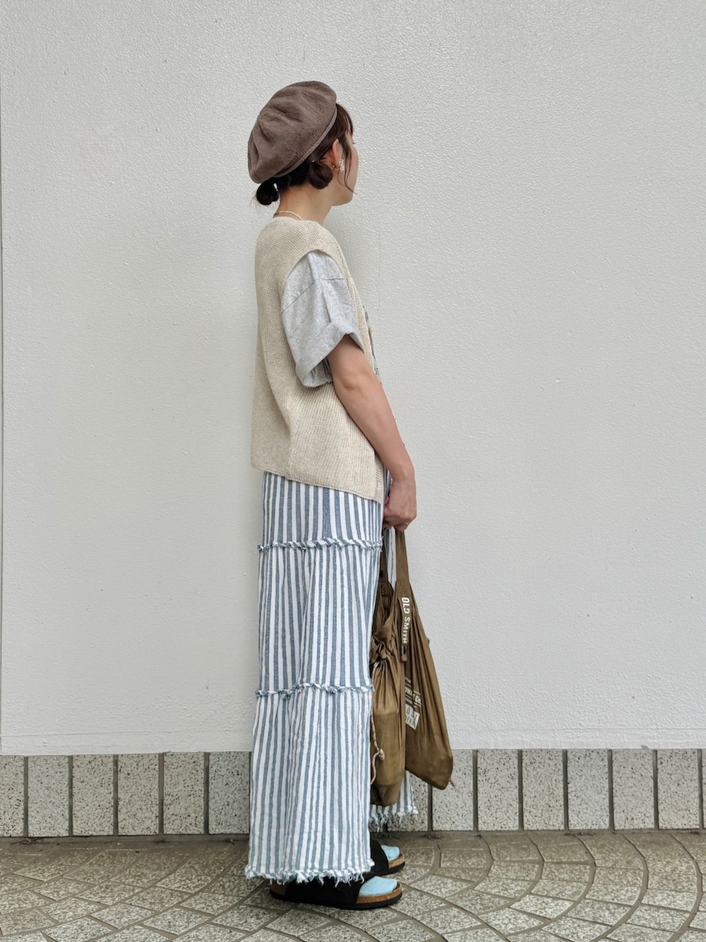 グレー系のTシャツ/カットソー、ホワイト系のベスト、ブラウン系のサンダルを着用したレディースの夏コーディネートの4枚目の写真