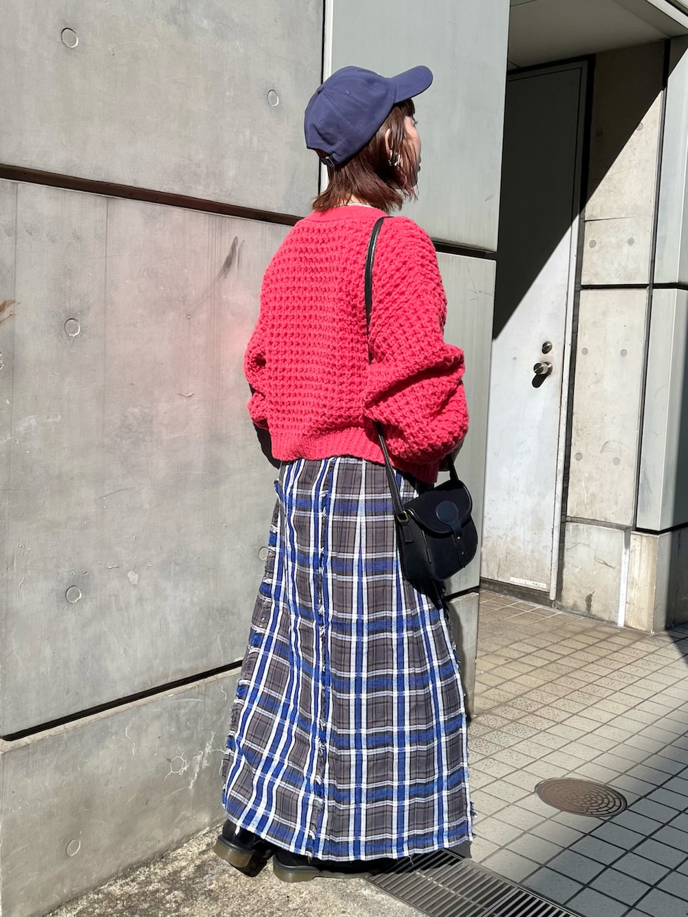 レッド系のカーディガン/ボレロ、ブルー系のスカート、ブラック系のローファーを着用したレディースの秋コーディネートの2枚目の写真