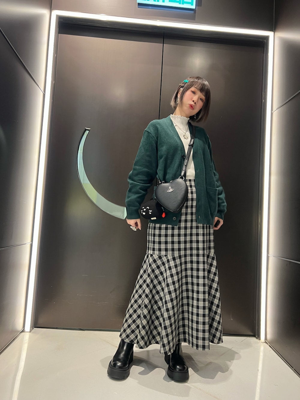 ブラック系のスカート、ブラック系のブーツ、グリーン系のジャケット/アウターを着用したレディースの冬コーディネートの2枚目の写真