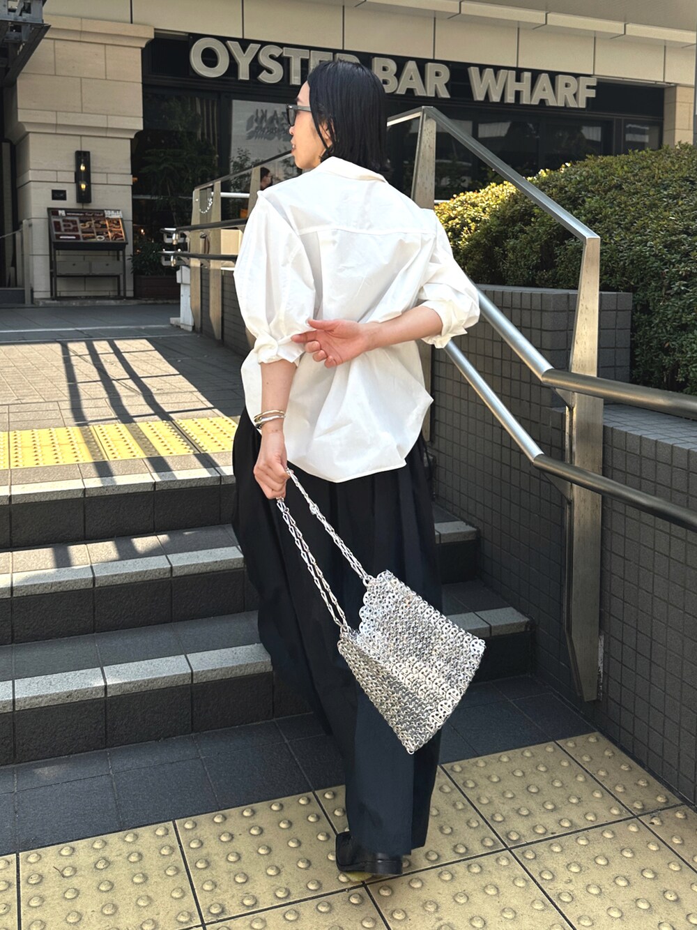 ブラック系のスカート、ホワイト系のシャツ/ブラウス、ブラック系のローファーを着用したレディースの春コーディネートの5枚目の写真