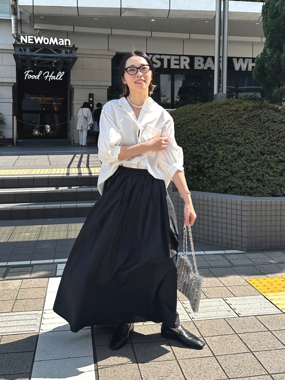 ブラック系のスカート、ホワイト系のシャツ/ブラウス、ブラック系のローファーを着用したレディースの春コーディネートの3枚目の写真