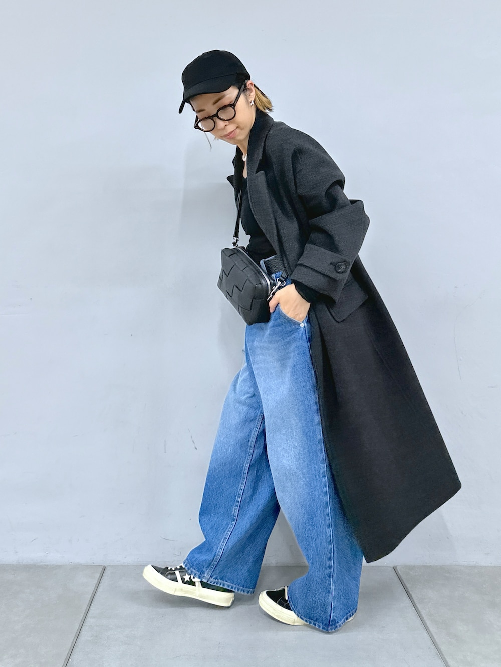 ブラック系のショルダーバッグ、ブルー系のデニムパンツ、グレー系のチェスターコートを着用したレディースの秋コーディネートの3枚目の写真