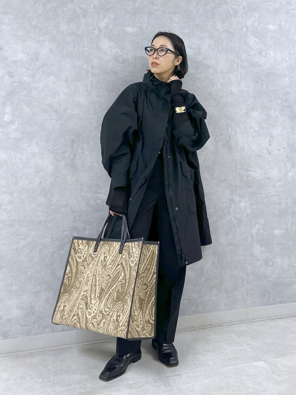 ブラック系のマウンテンパーカー、ブラック系のスラックス、ブラック系のトートバッグを着用したレディースの春コーディネートの2枚目の写真