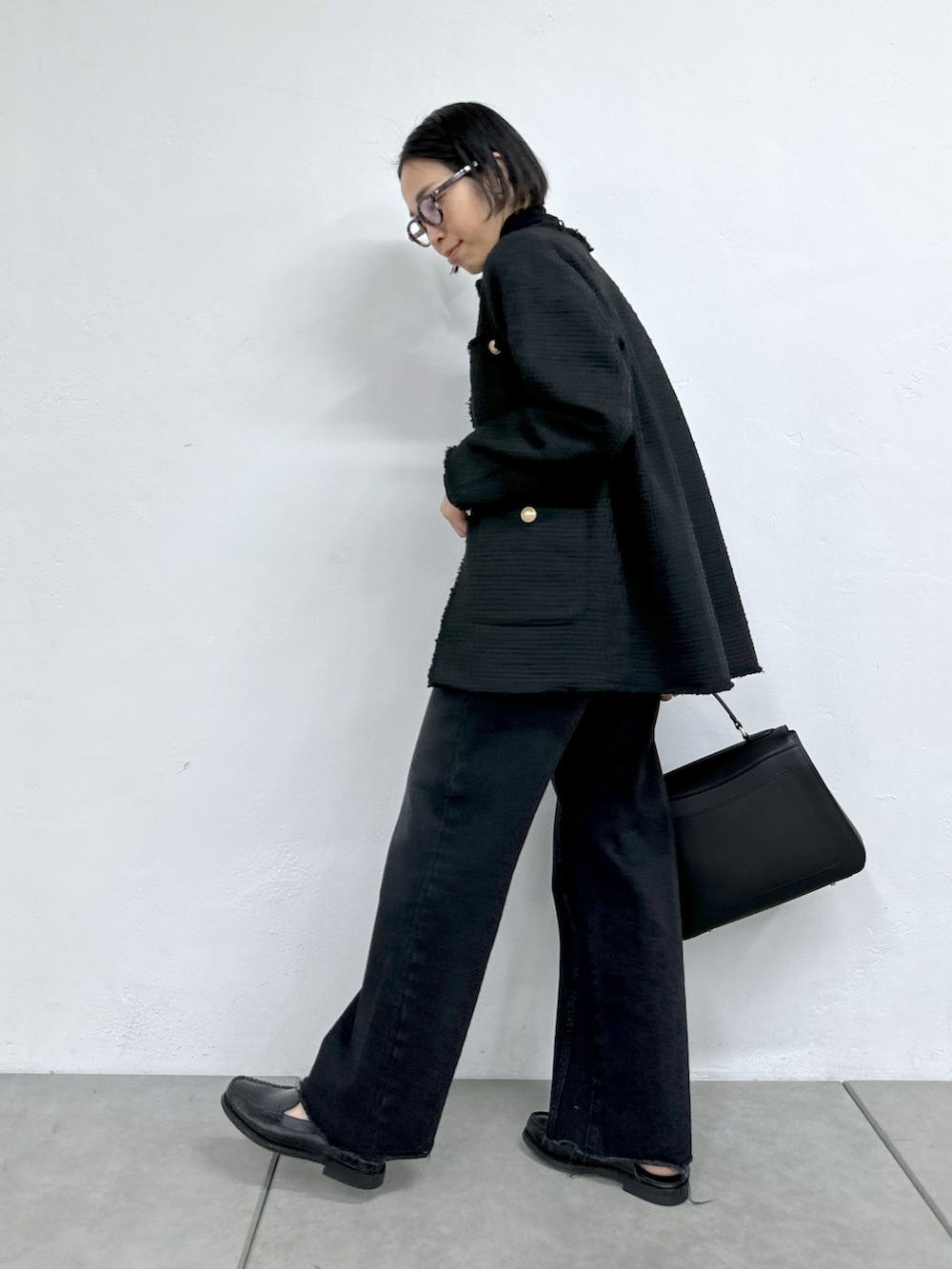 ブラック系のトートバッグ、ブラック系のデニムパンツ、ブラック系のローファーを着用したレディースの秋コーディネートの2枚目の写真