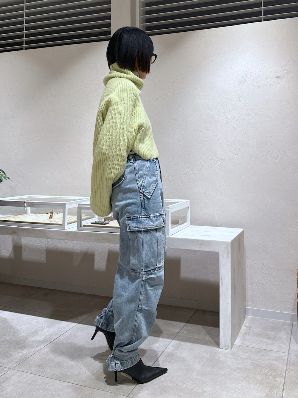 グリーン系のニット/セーター、ホワイト系のニット/セーター、ブルー系のデニムパンツを着用したレディースの冬コーディネートの2枚目の写真